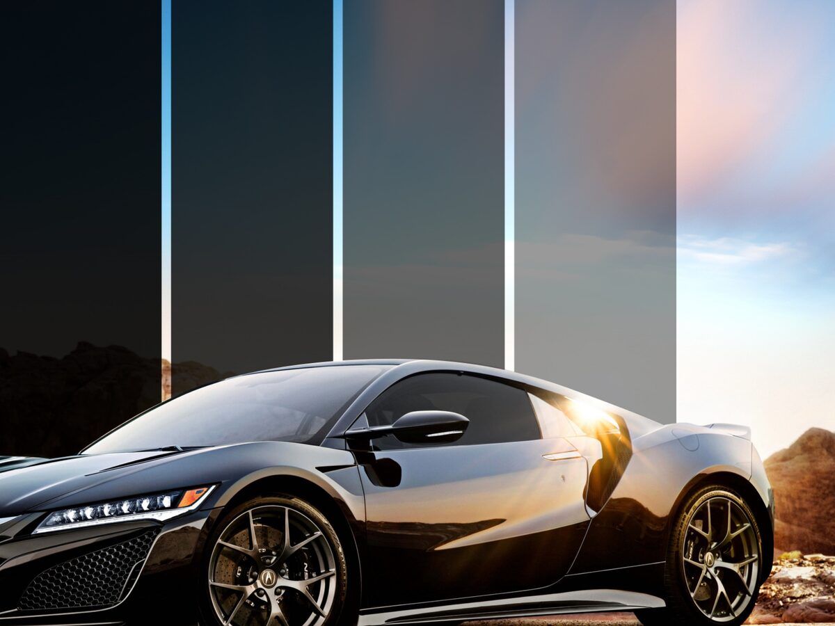A black sports car shown behind window tint strips of different darkness levels