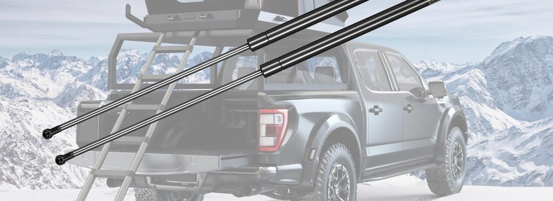 A pair of IAQWE gas struts in front of a pickup truck with a rooftop camper in snowy mountains
